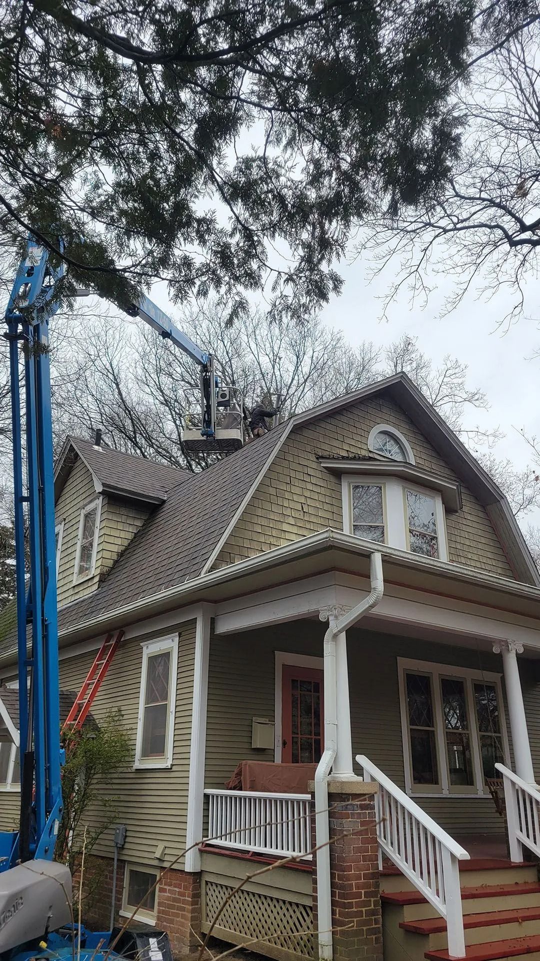 Small Victorian house with a steep roof and front porch, surrounded by leafless trees.