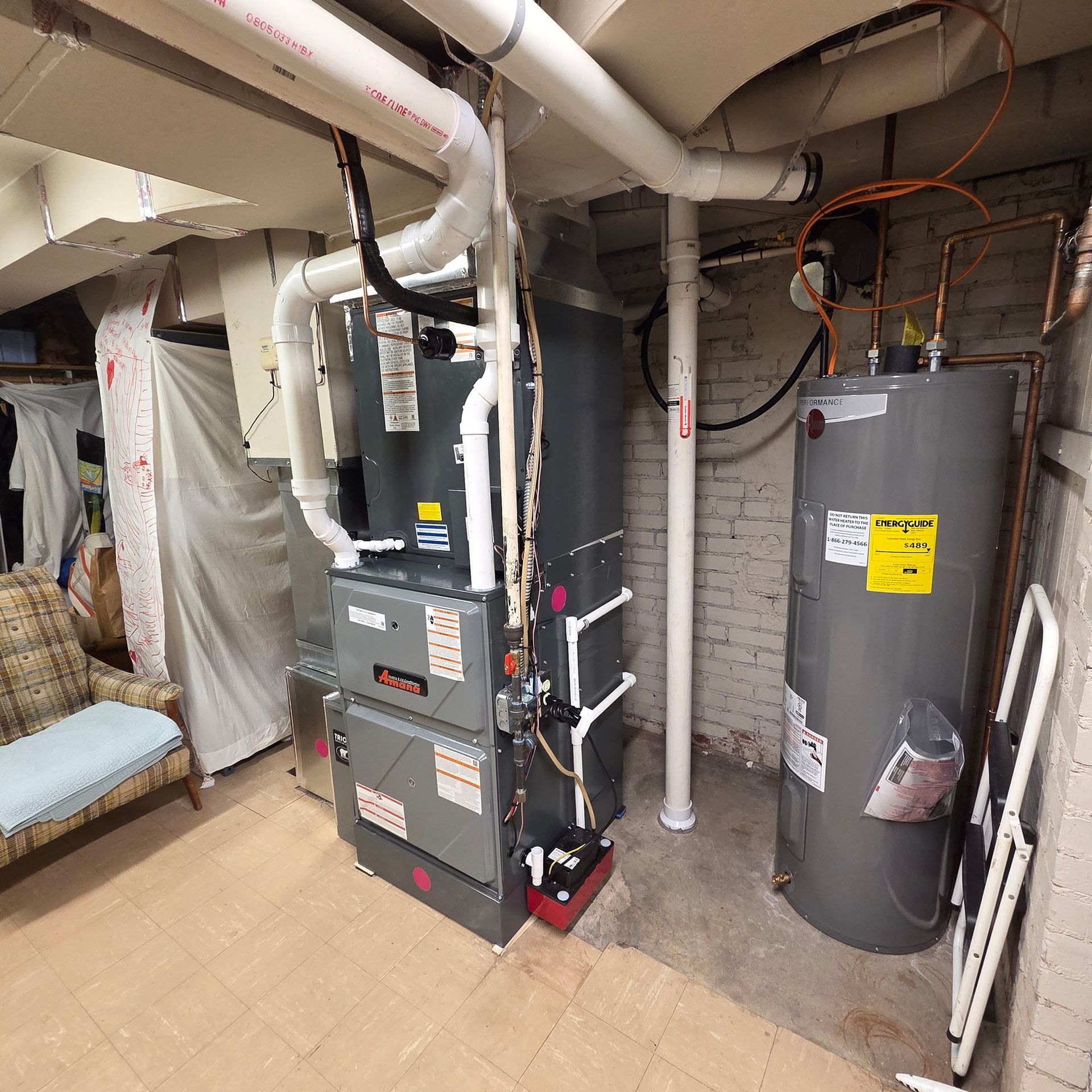 Basement mechanical room with furnace, water heater, and exposed pipes along unfinished walls.