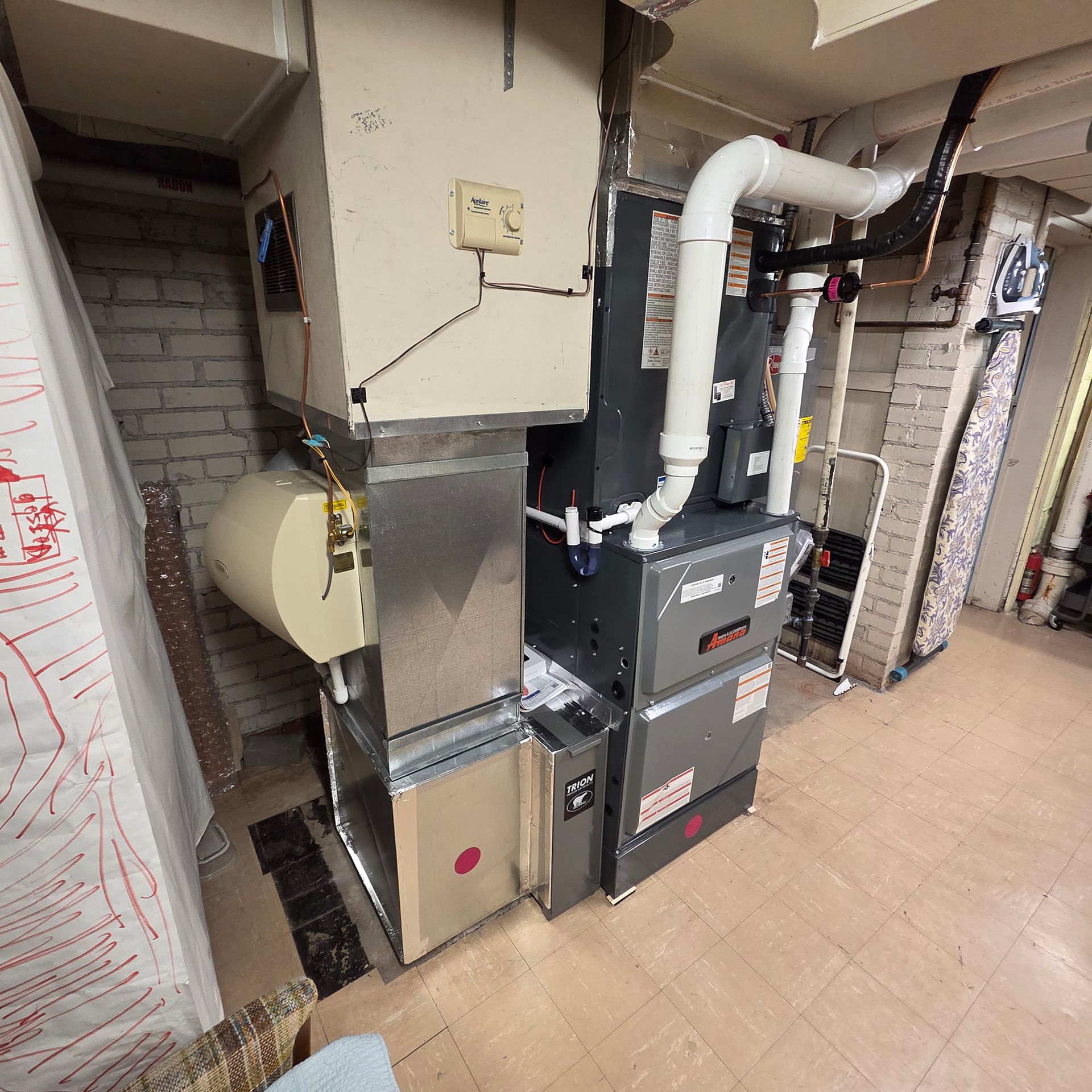 Indoor mechanical room with gray HVAC and boiler units, white ductwork, and tiled floor