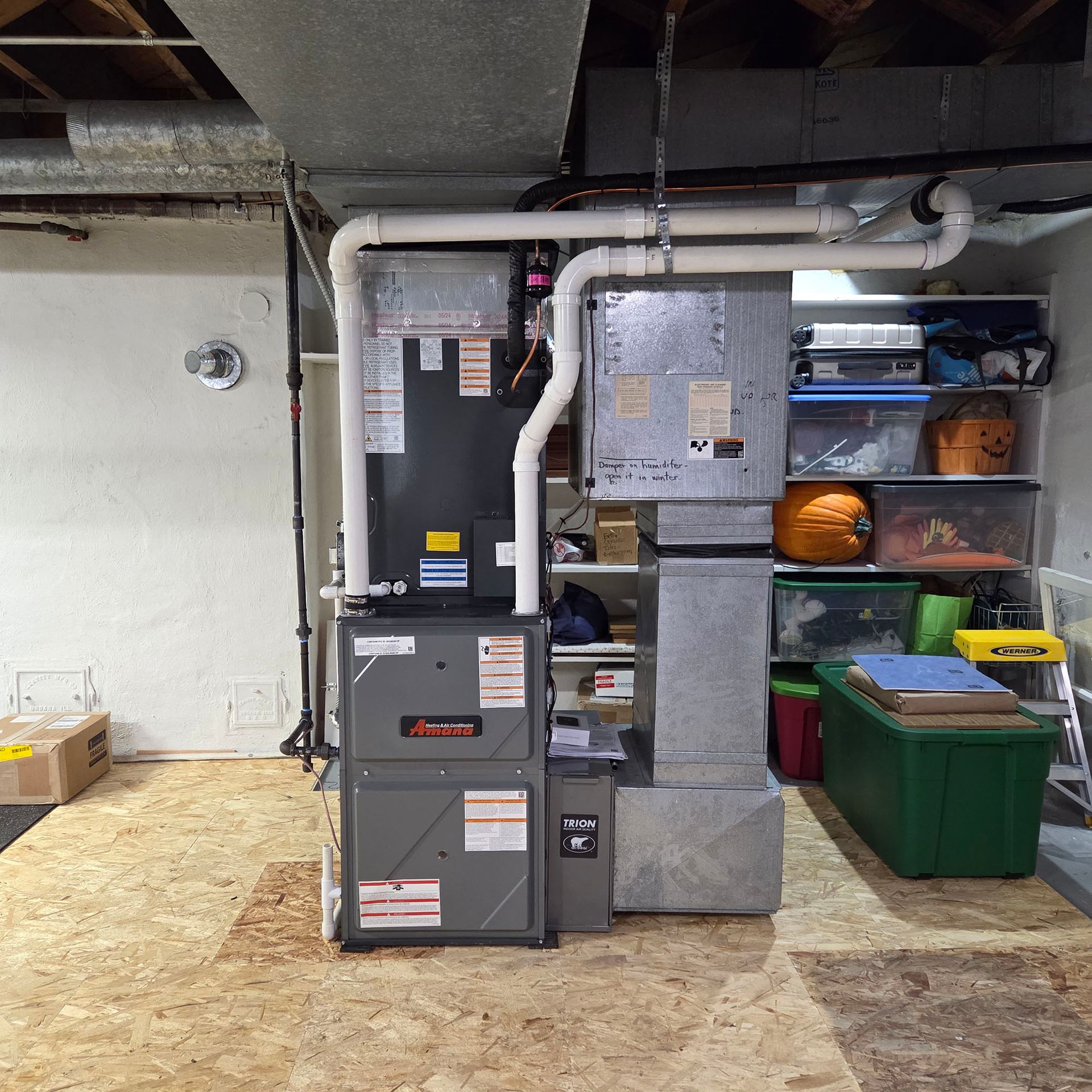 Basement utility area with furnace, ductwork, and storage bins beside a concrete wall