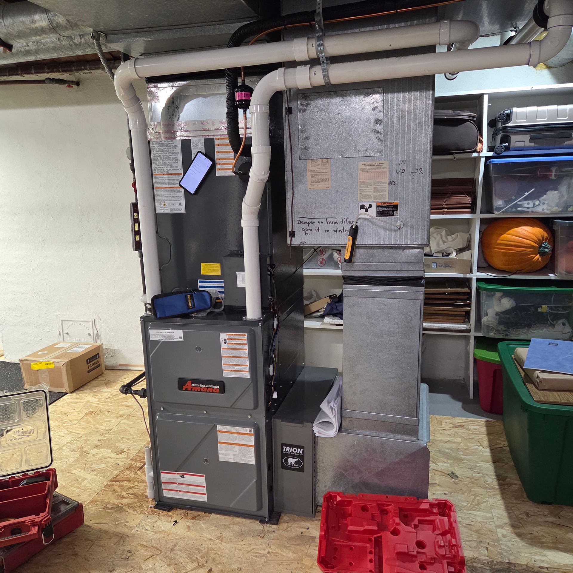 Utility room with furnace, ductwork, shelves, and red storage bins on the floor