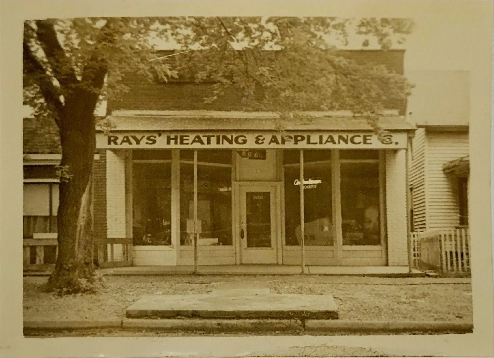 Sepia photo of Ray’s Heating & Appliance storefront with trees and neighboring buildings
