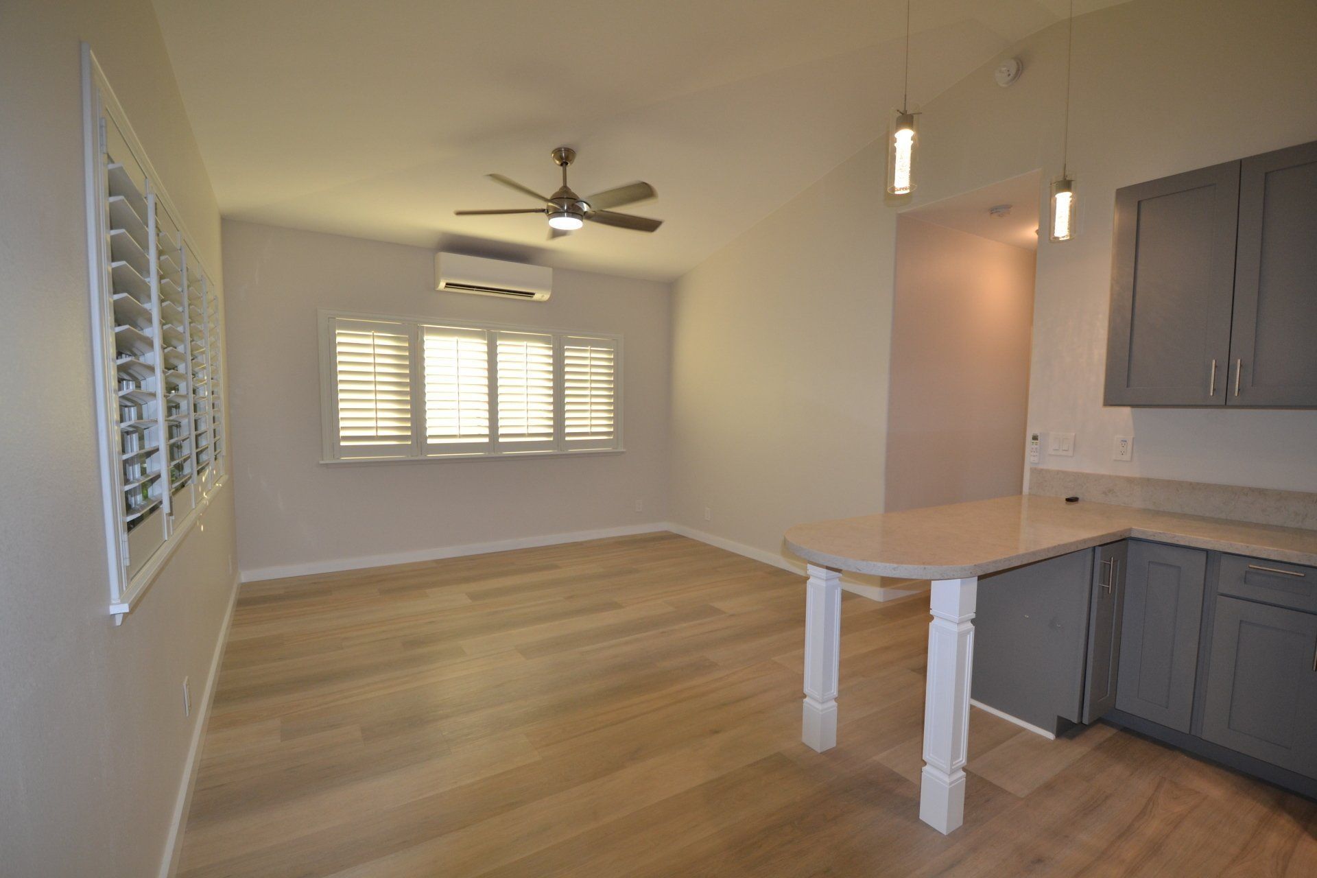 An empty living room with hardwood floors and a ceiling fan.