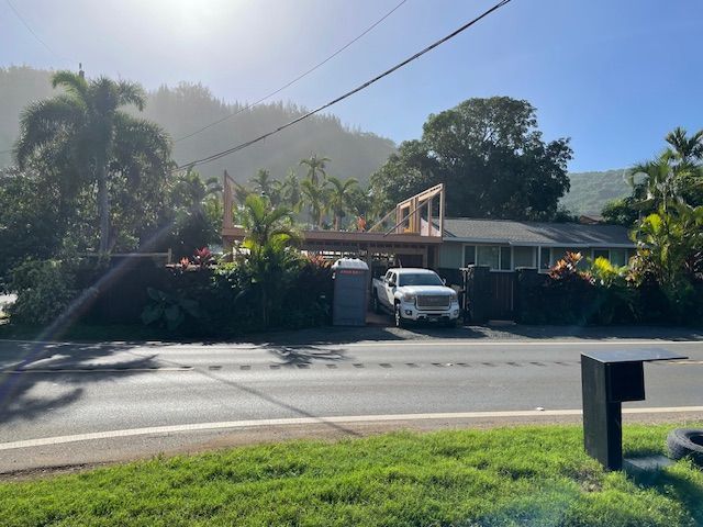 A white truck is parked in front of a house on the side of the road.