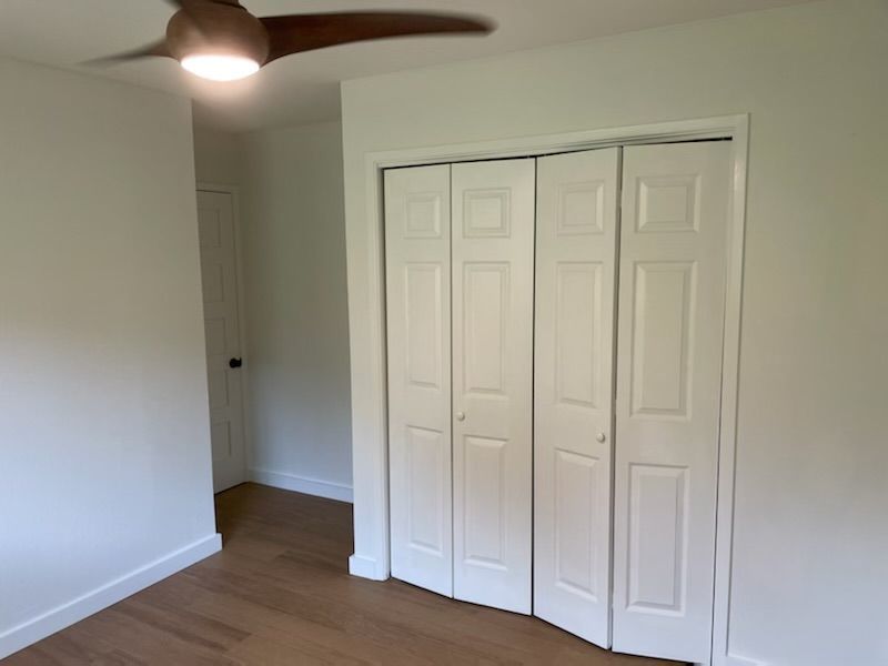 There is a ceiling fan in the room with a closet.