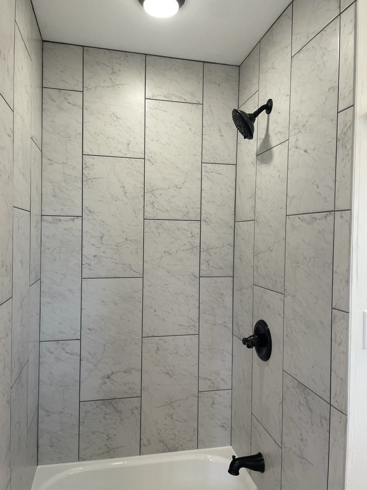 A bathroom with a tub and a shower with marble tiles