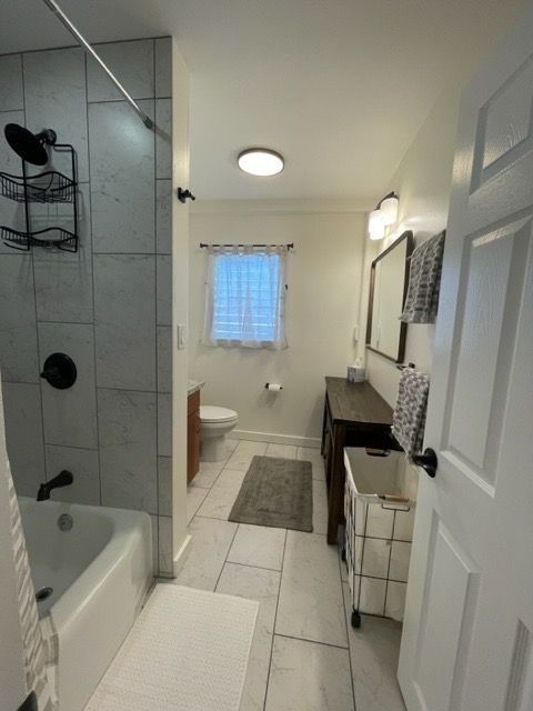 A bathroom with a tub a toilet and a mirror