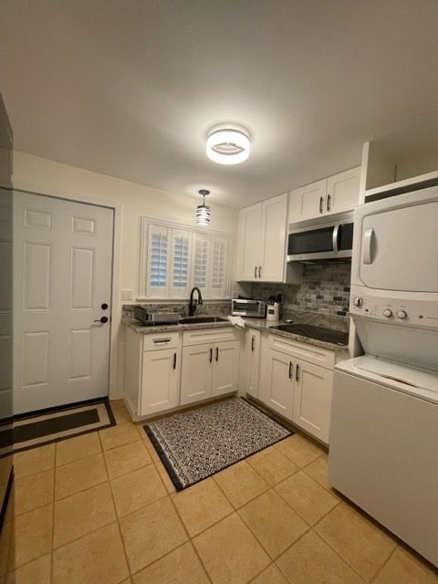 A kitchen with white cabinets and a washer and dryer