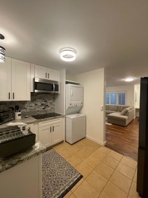 A kitchen with white cabinets and a washer and dryer