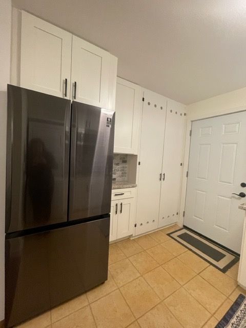 A kitchen with a black refrigerator and white cabinets