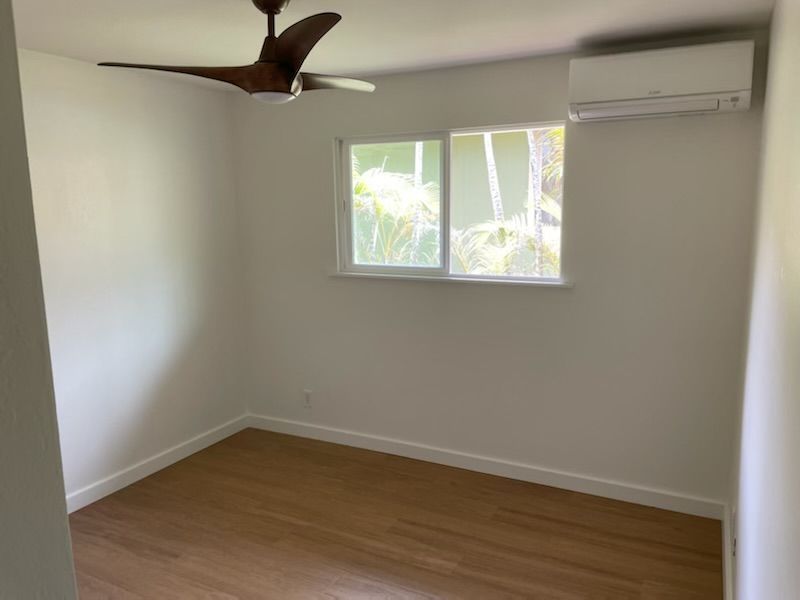 An empty room with a ceiling fan and a window.