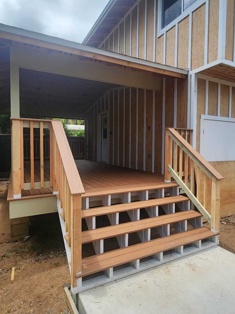 A house under construction with a wooden deck and stairs.