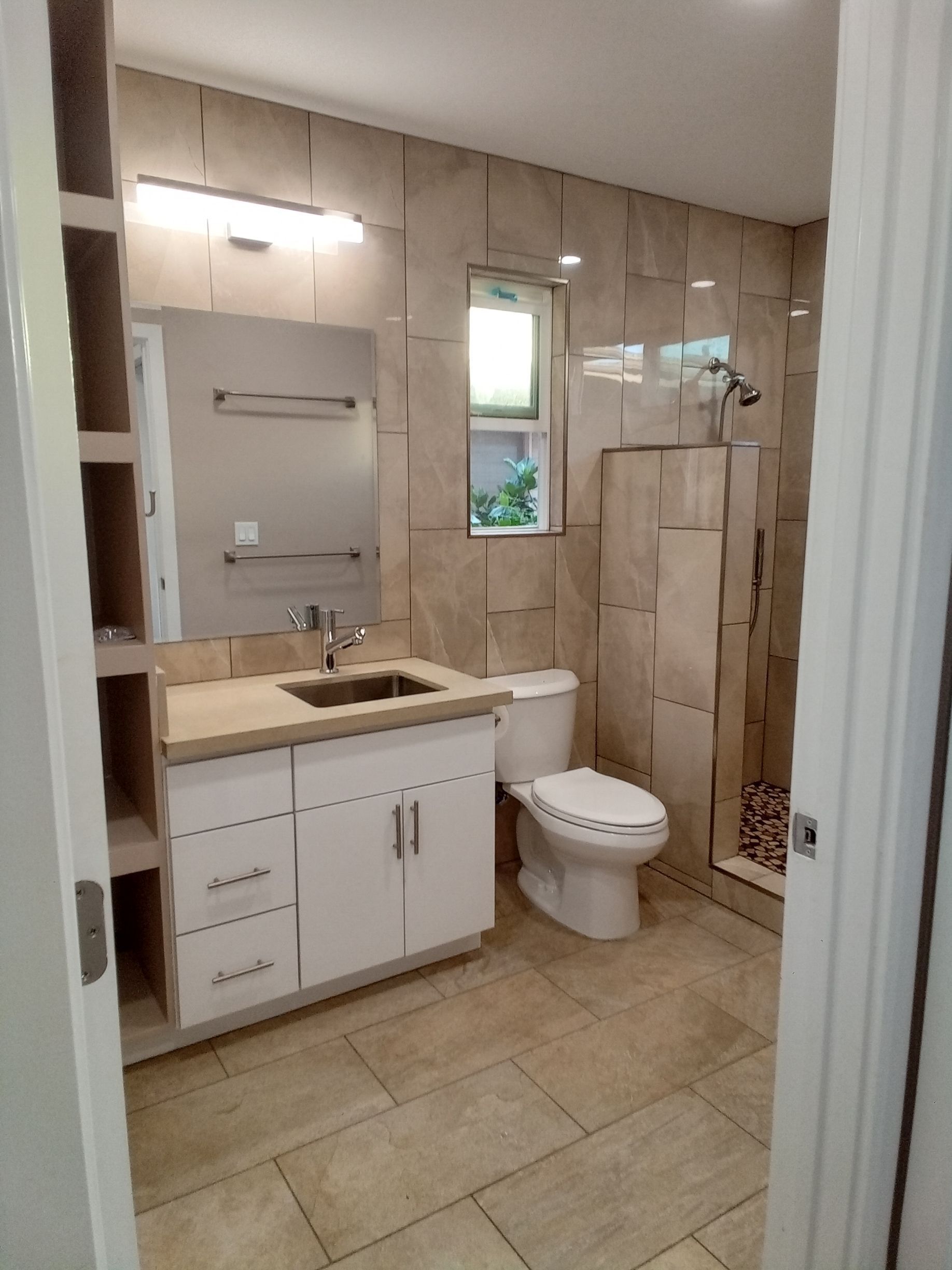 A bathroom with a toilet , sink , mirror and shower.