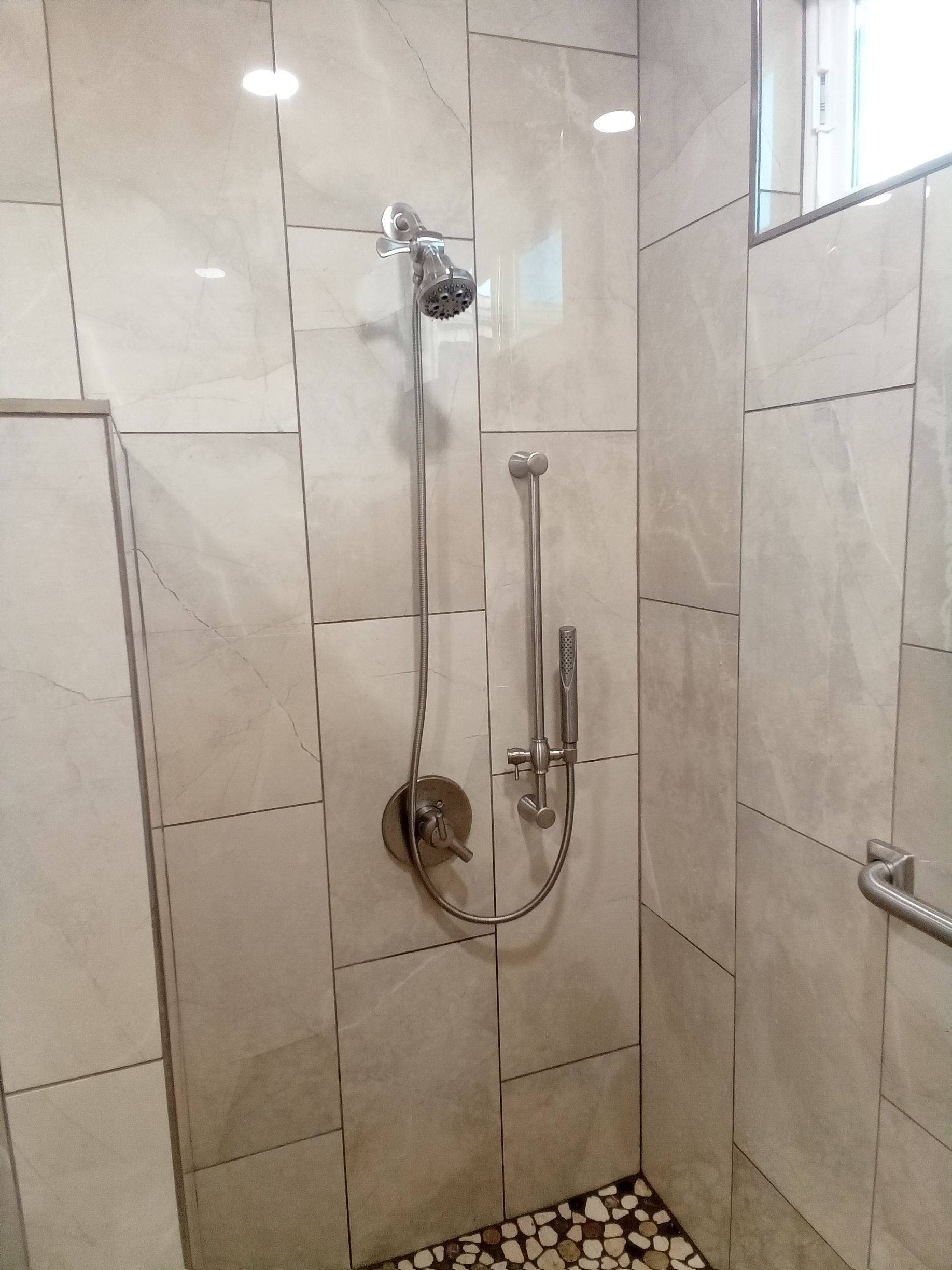 A bathroom with white tiles and a shower head