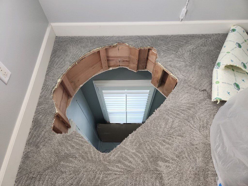 A hole in the carpet in a room with a window.