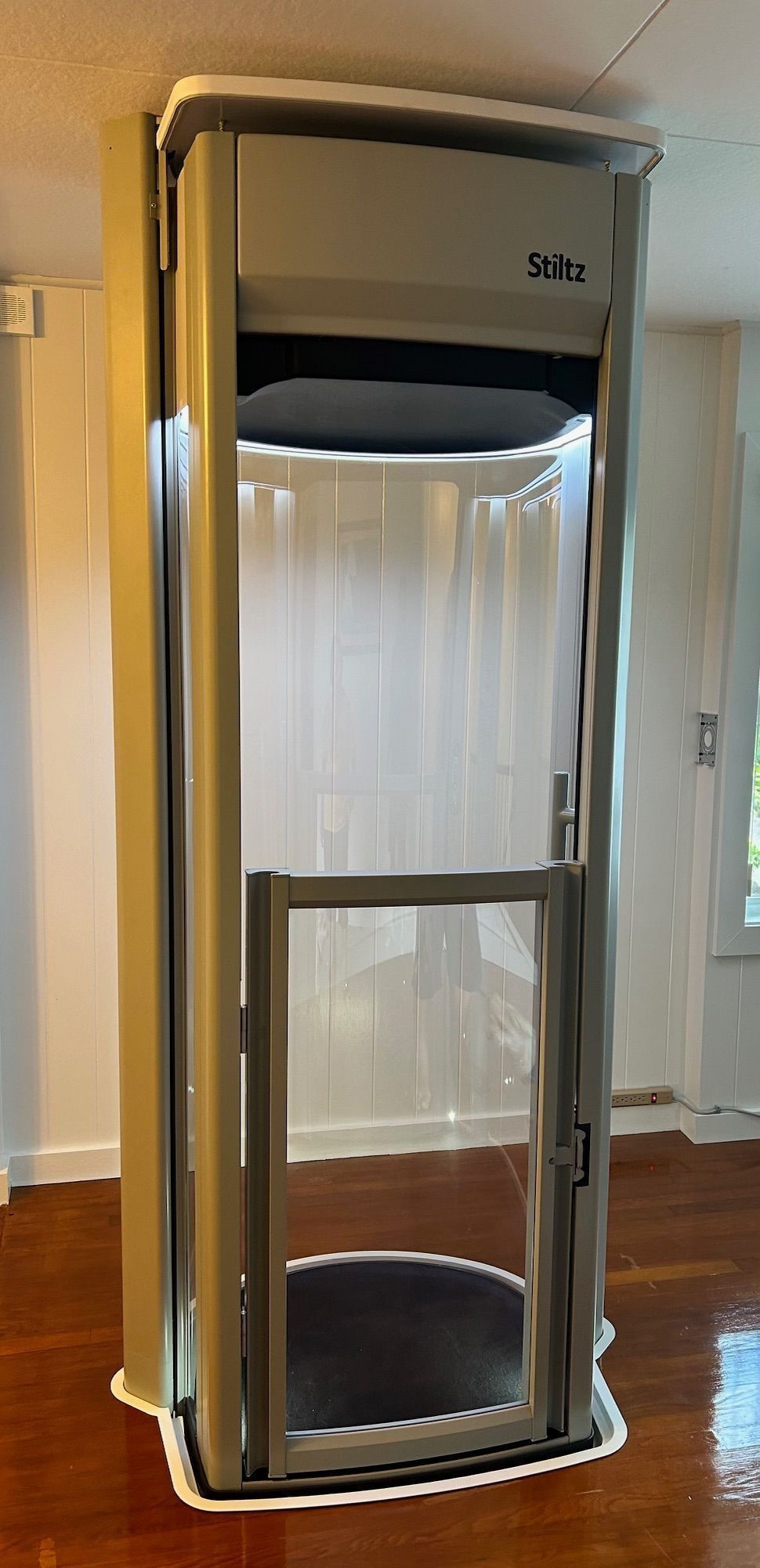 A small elevator is sitting on top of a wooden floor in a room.