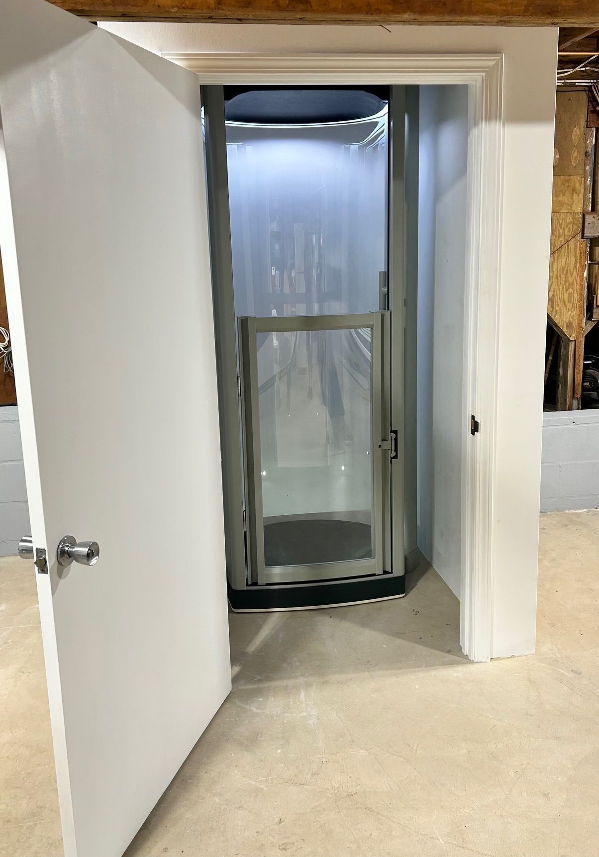 A small elevator in a basement with a door open.