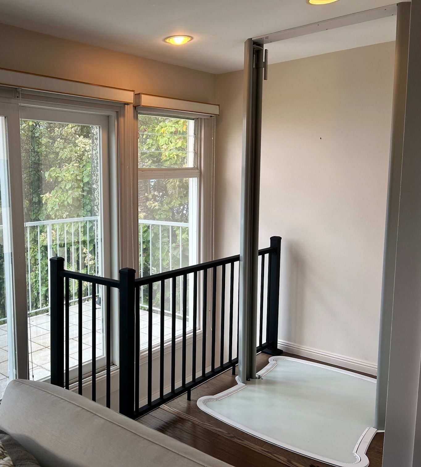 A room with a staircase leading to a balcony and a sliding glass door.