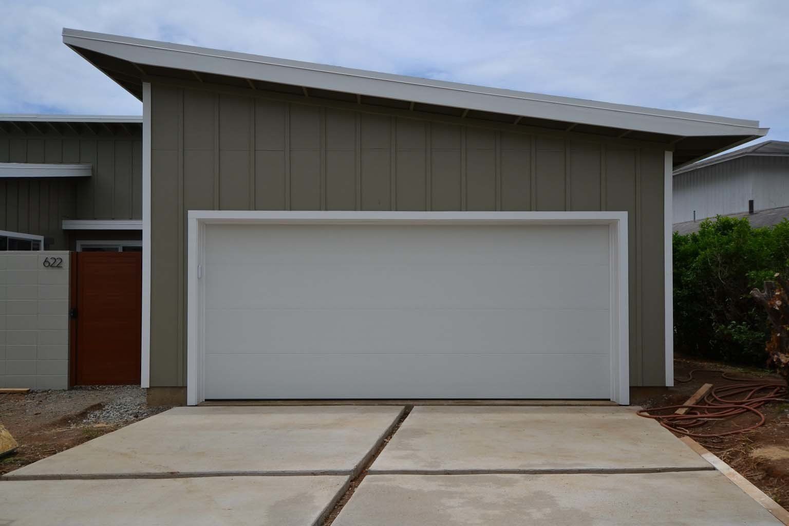 A white garage door is sitting in front of a house.