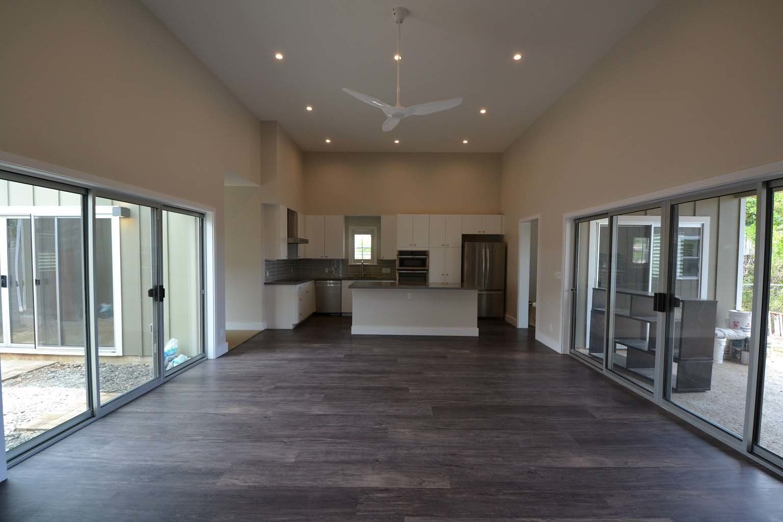 A large empty room with sliding glass doors and a ceiling fan.