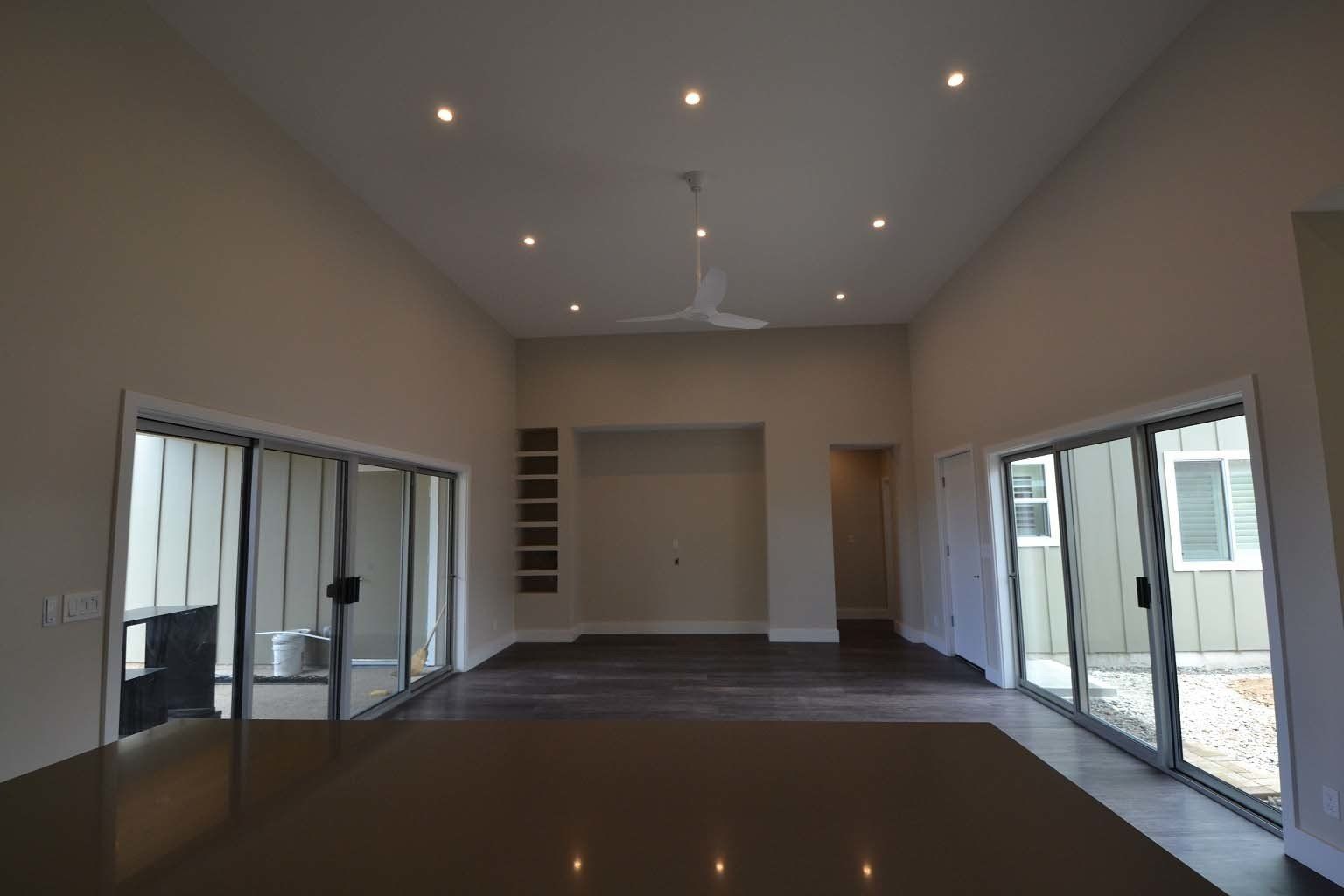 A large empty room with sliding glass doors and a ceiling fan.