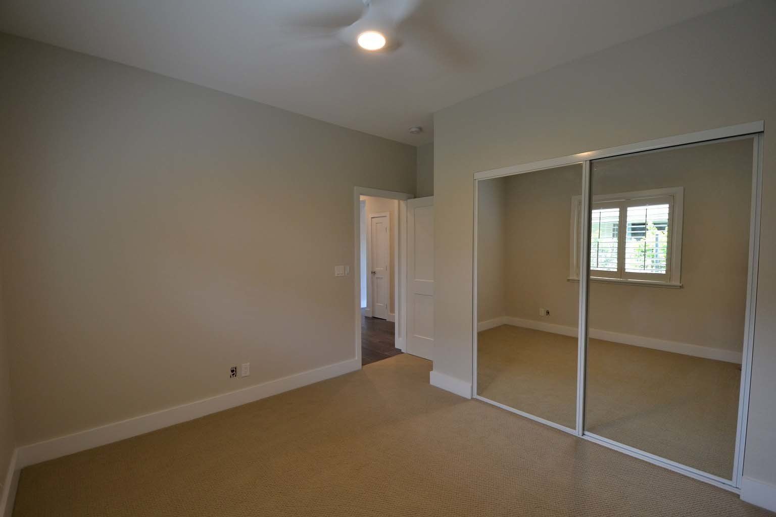 An empty bedroom with sliding glass doors and a window.
