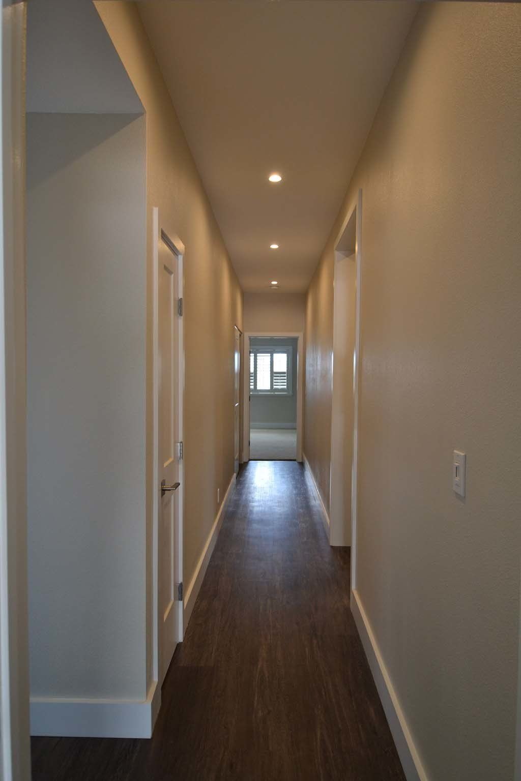 A long hallway with wooden floors and white walls in a house.
