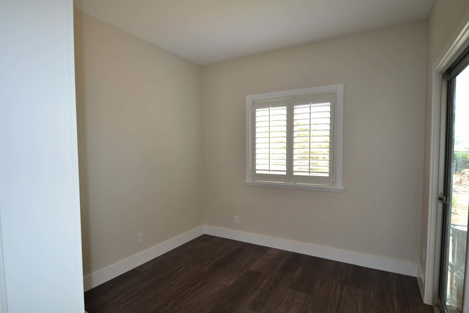 An empty room with hardwood floors and a window.