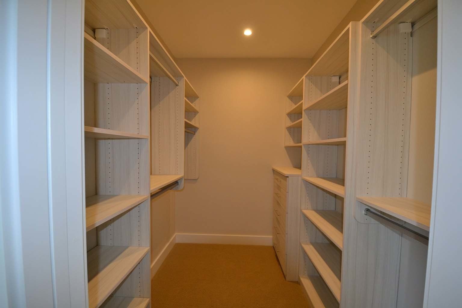 A walk in closet with lots of shelves and drawers