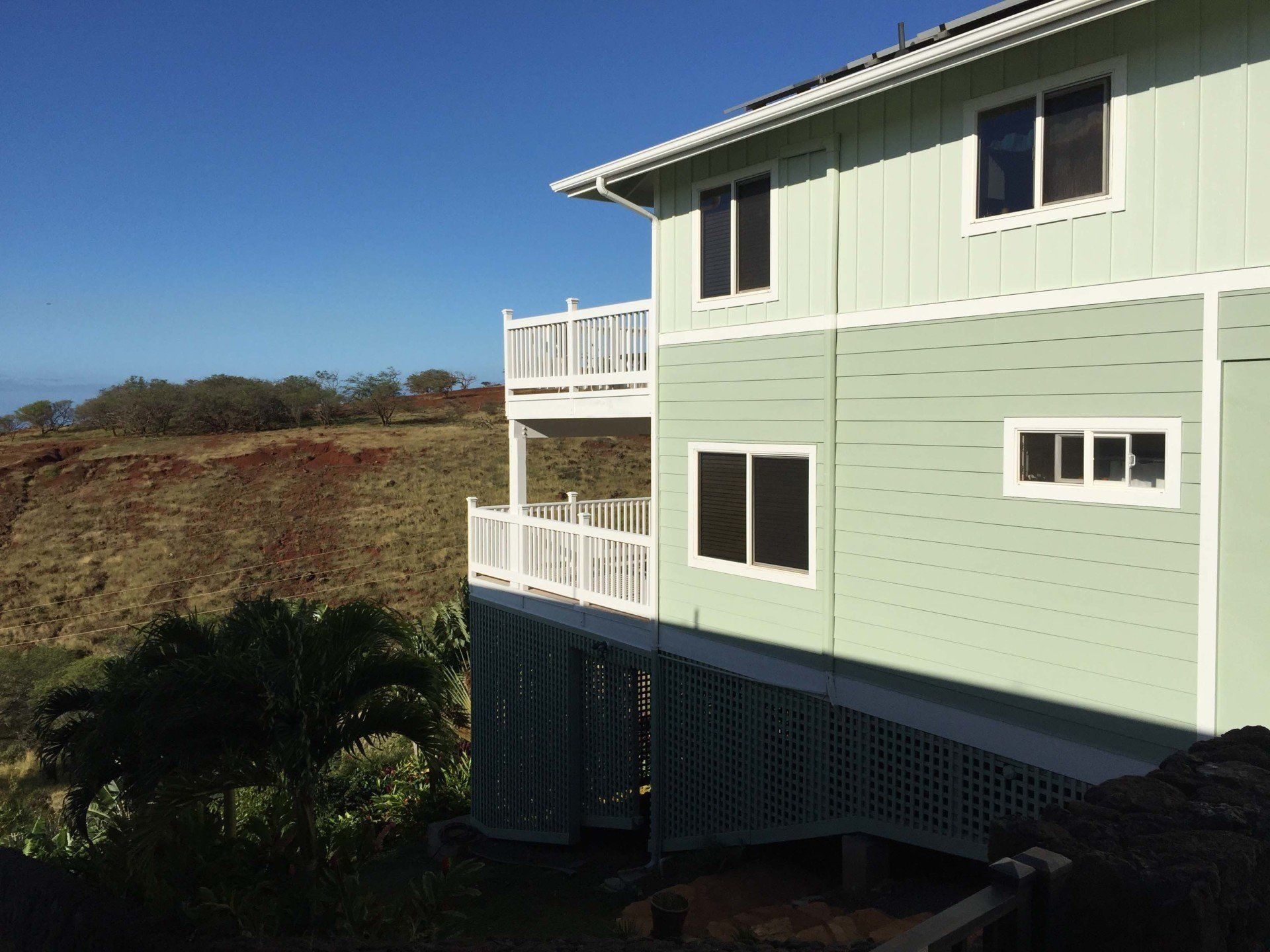 A green house with a balcony on the side of it