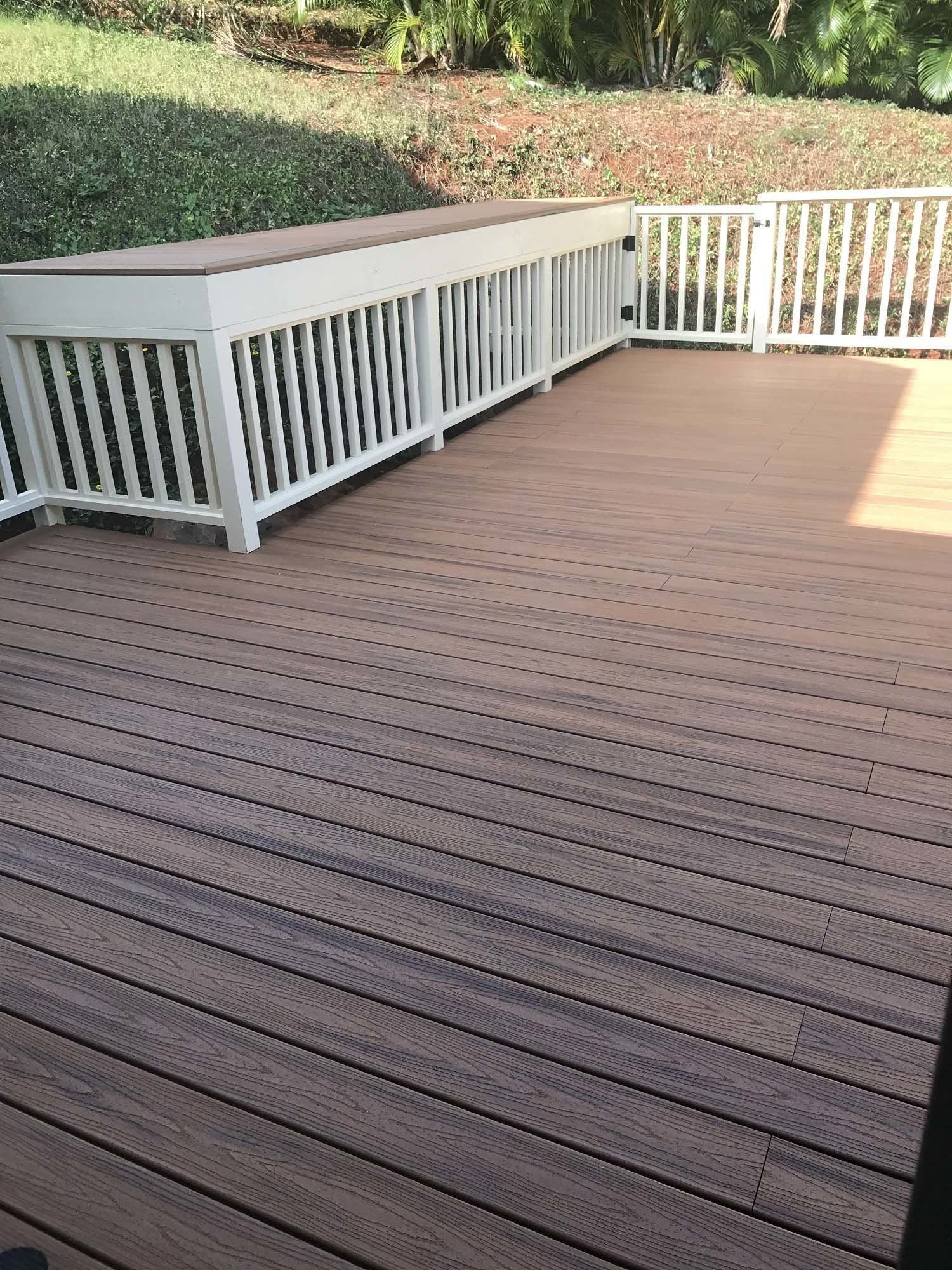 A wooden deck with a white railing and a bench.