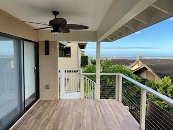 A balcony with a ceiling fan and a view of the ocean
