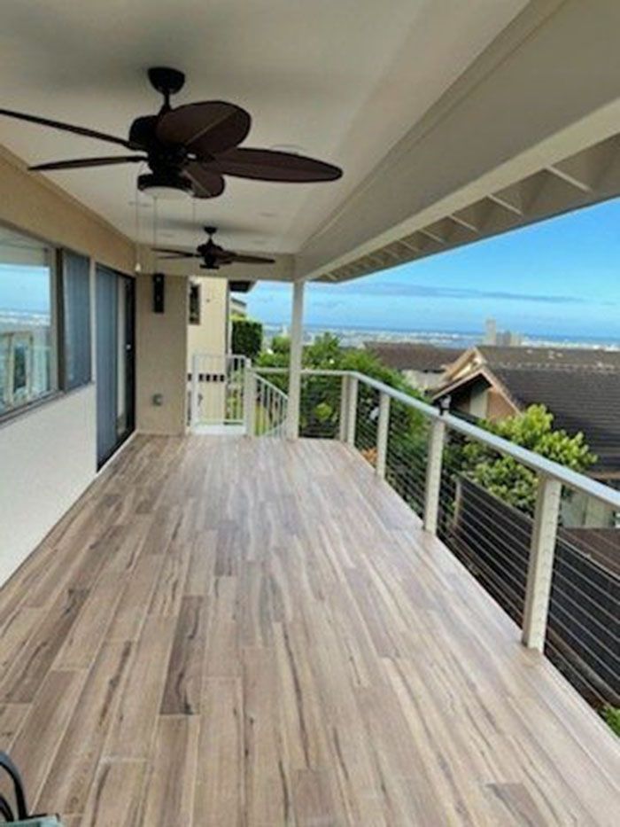 A balcony with a ceiling fan and a view of the ocean.