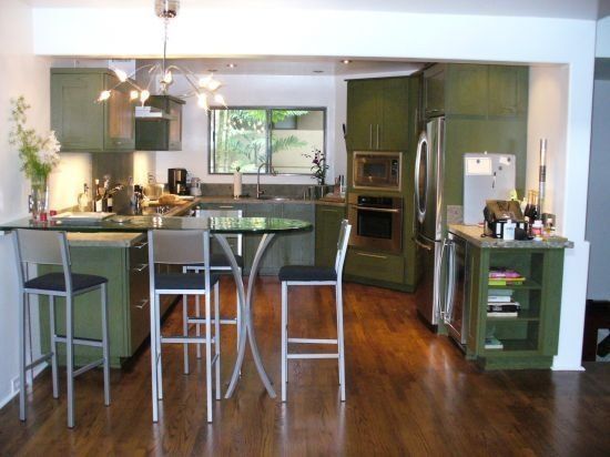 A kitchen with green cabinets and stainless steel appliances