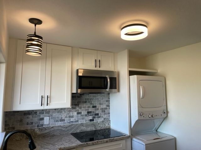 A kitchen with white cabinets and a washer and dryer