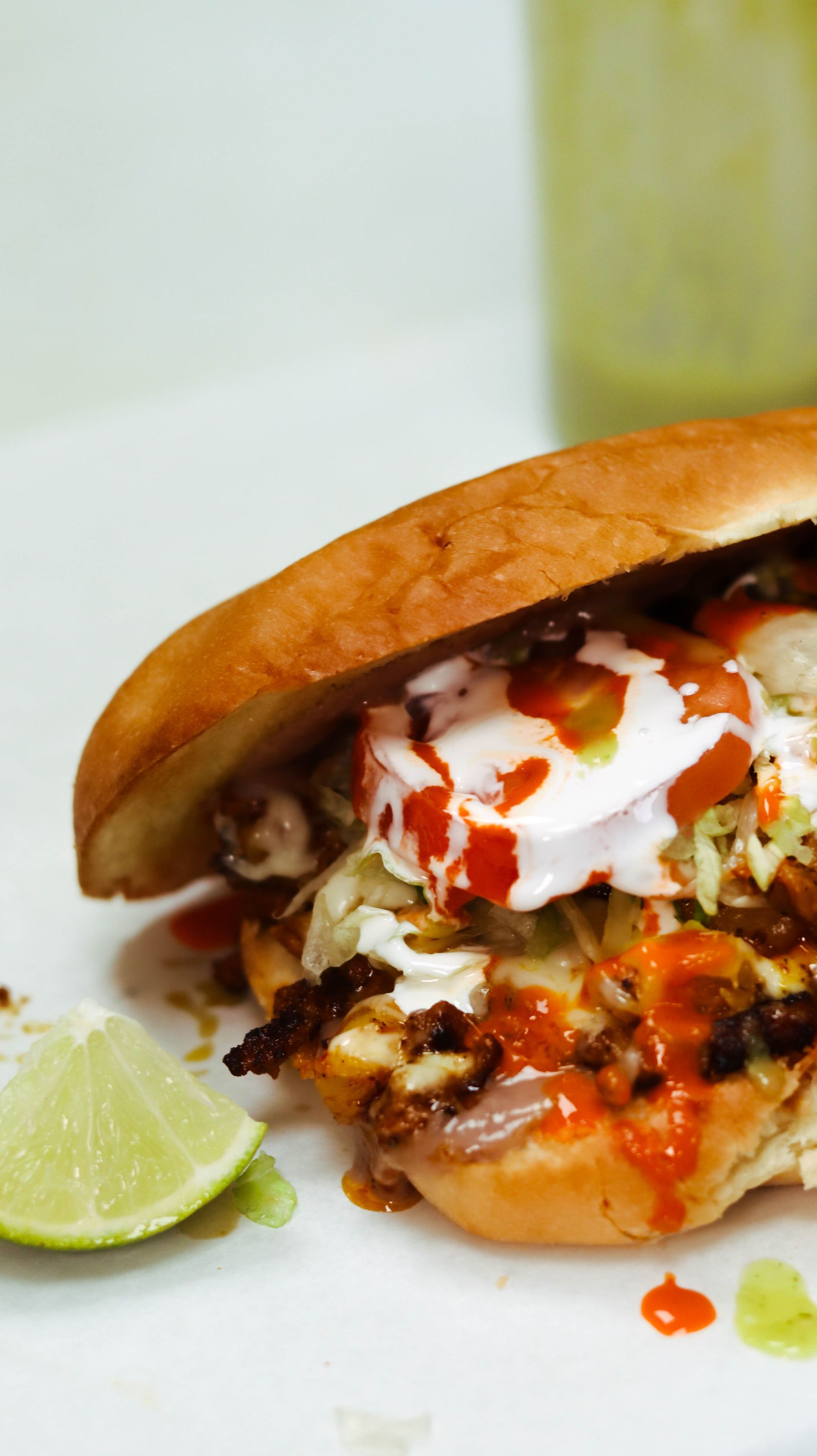 A close up of a sandwich on a plate with a lime wedge.