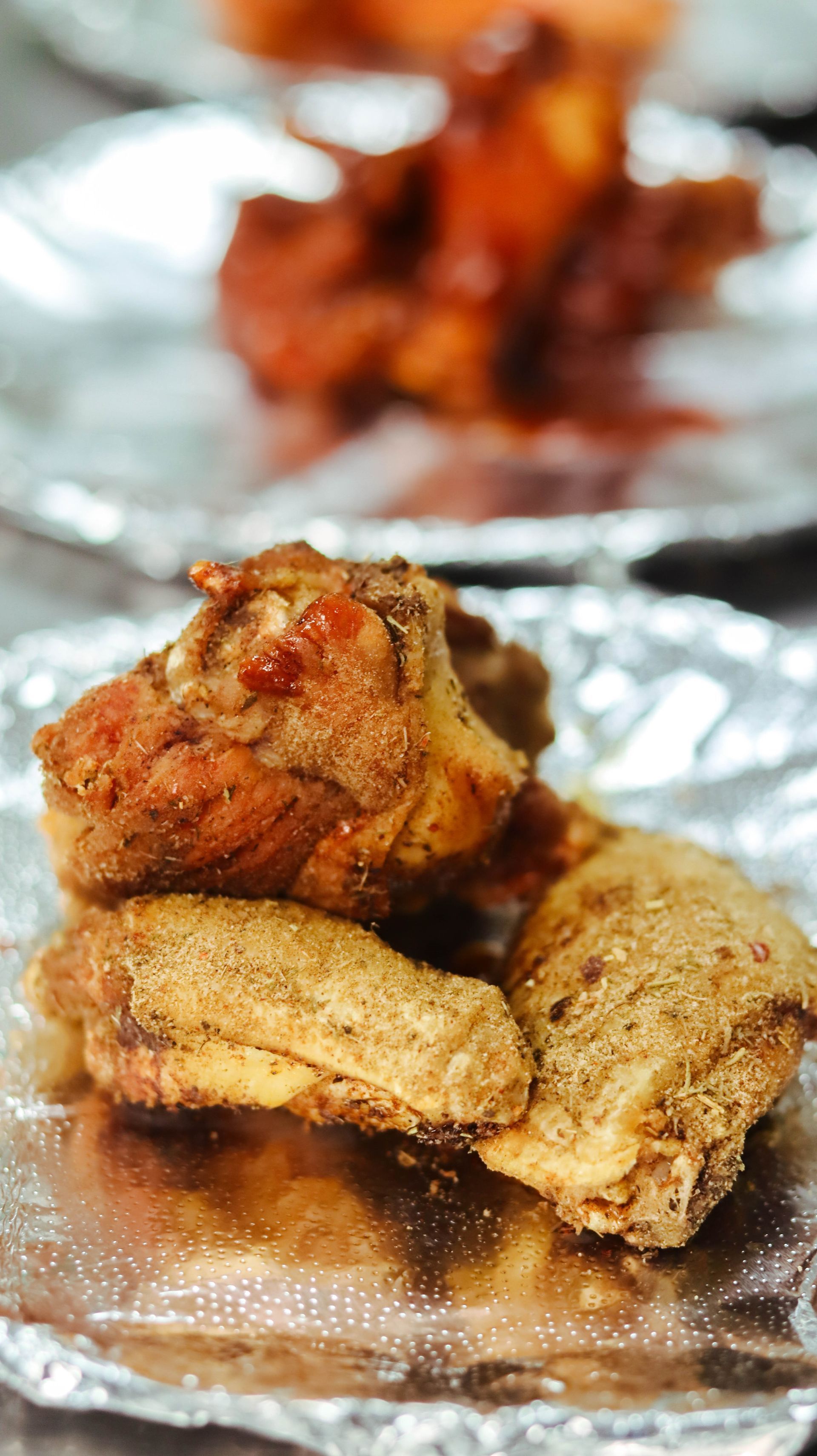 A close up of fried chicken wings on a piece of tin foil.