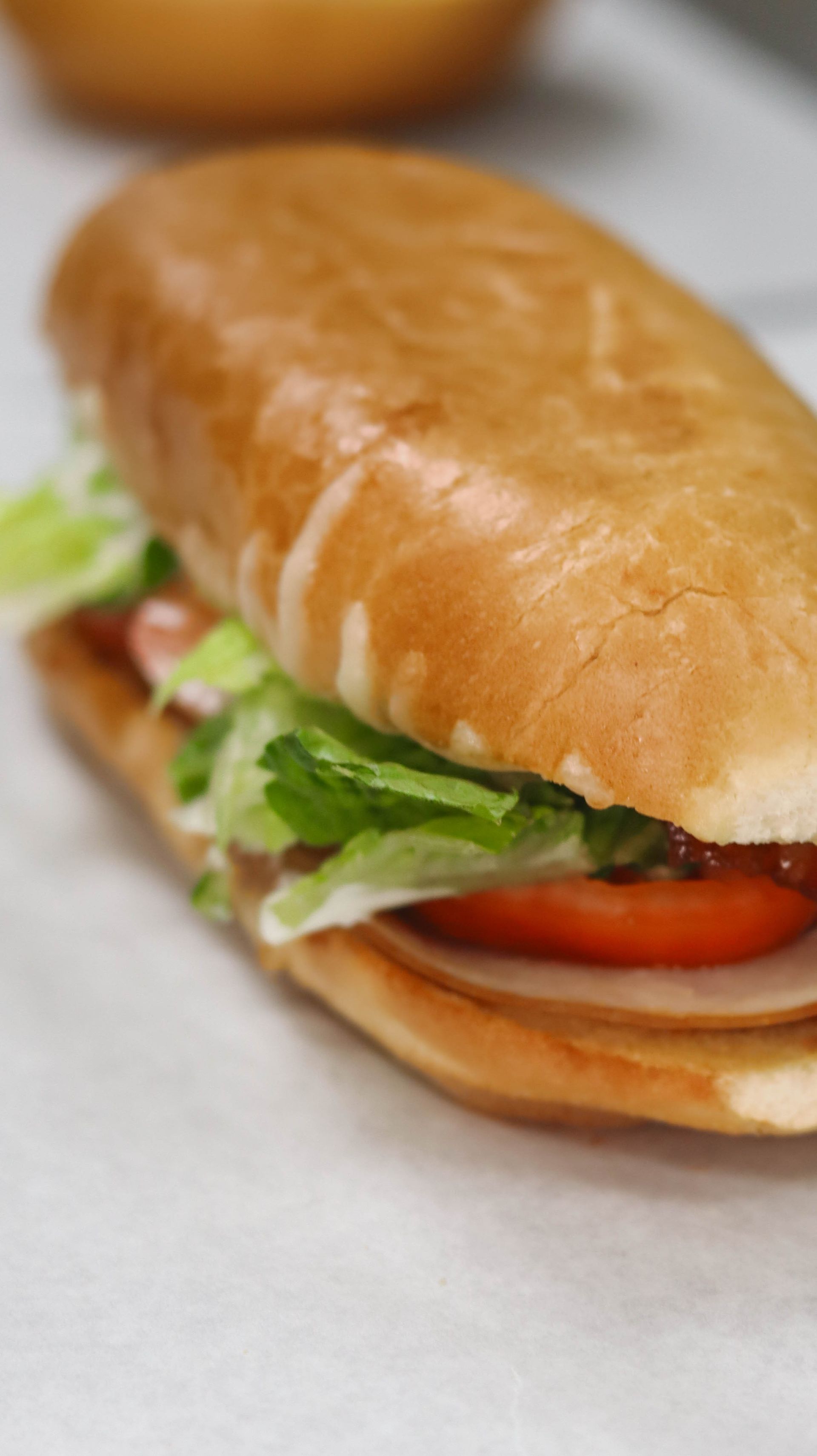 A sub sandwich with lettuce , tomatoes and ham is on a table.