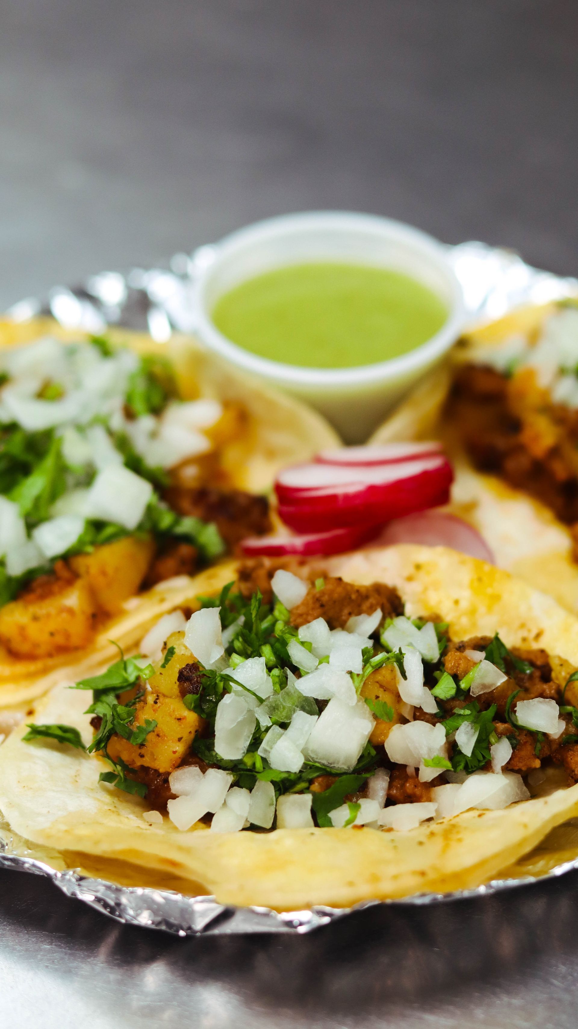A close up of a plate of tacos with a dipping sauce on a table.