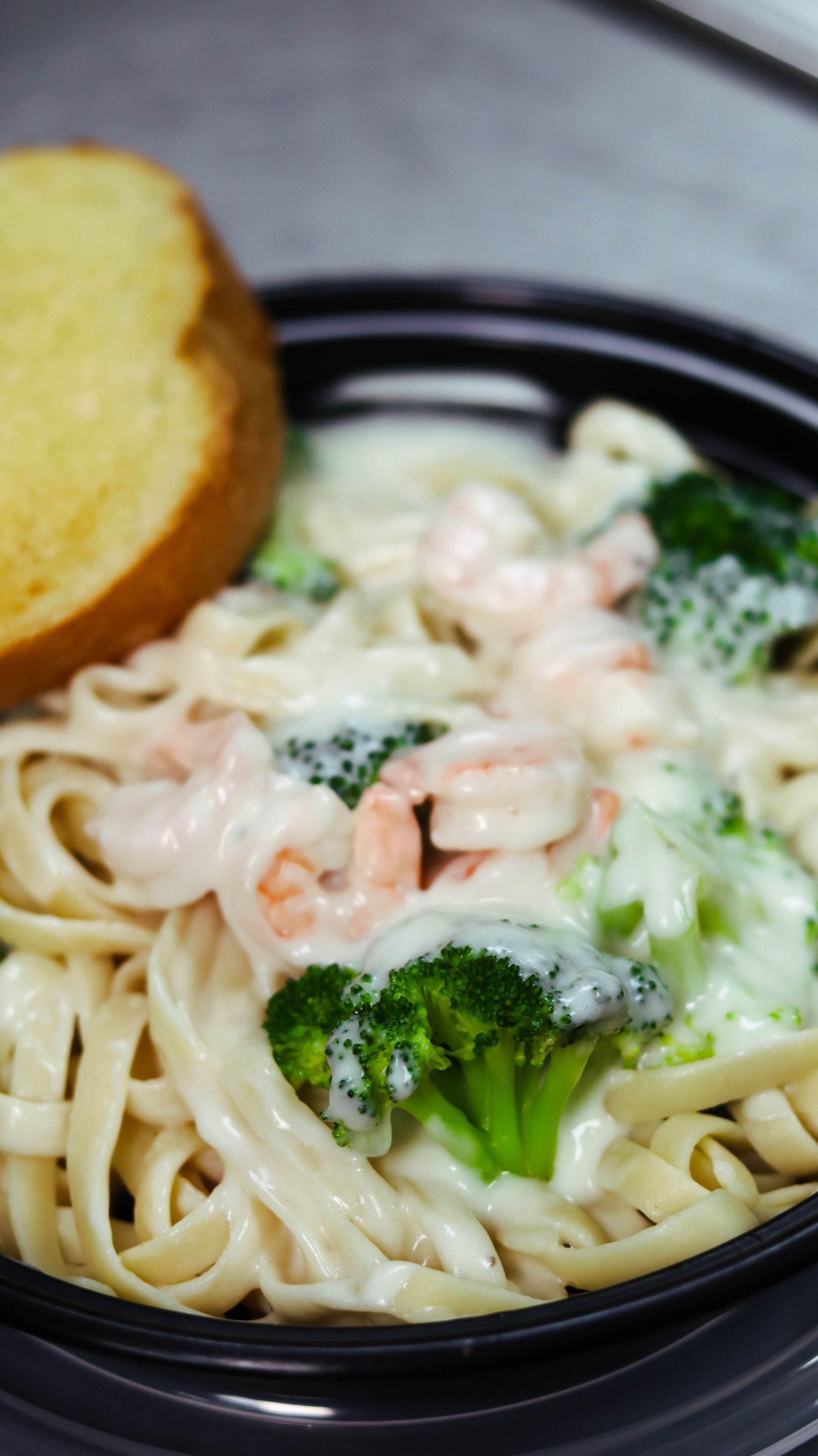 A close up of a bowl of pasta with broccoli and shrimp.