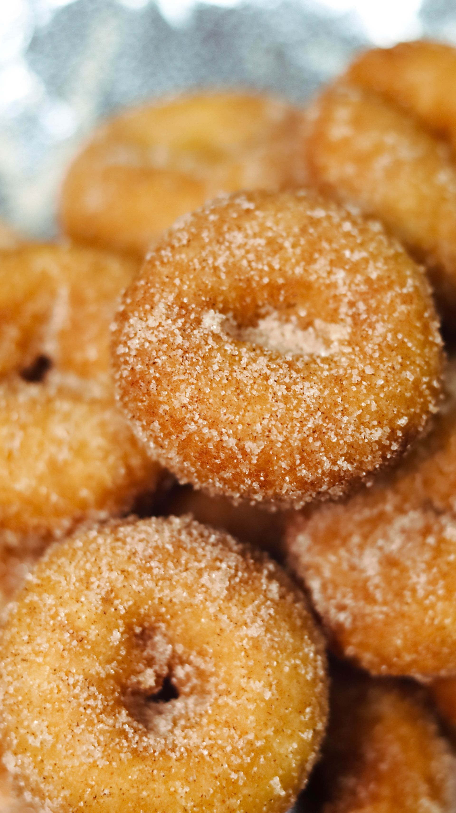 A close up of a pile of donuts covered in sugar.