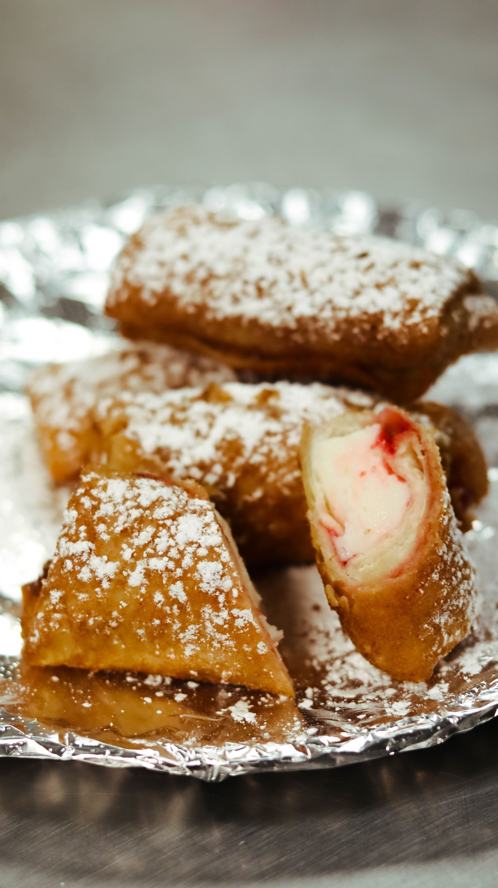 A close up of a plate of cannoli with powdered sugar on a table.