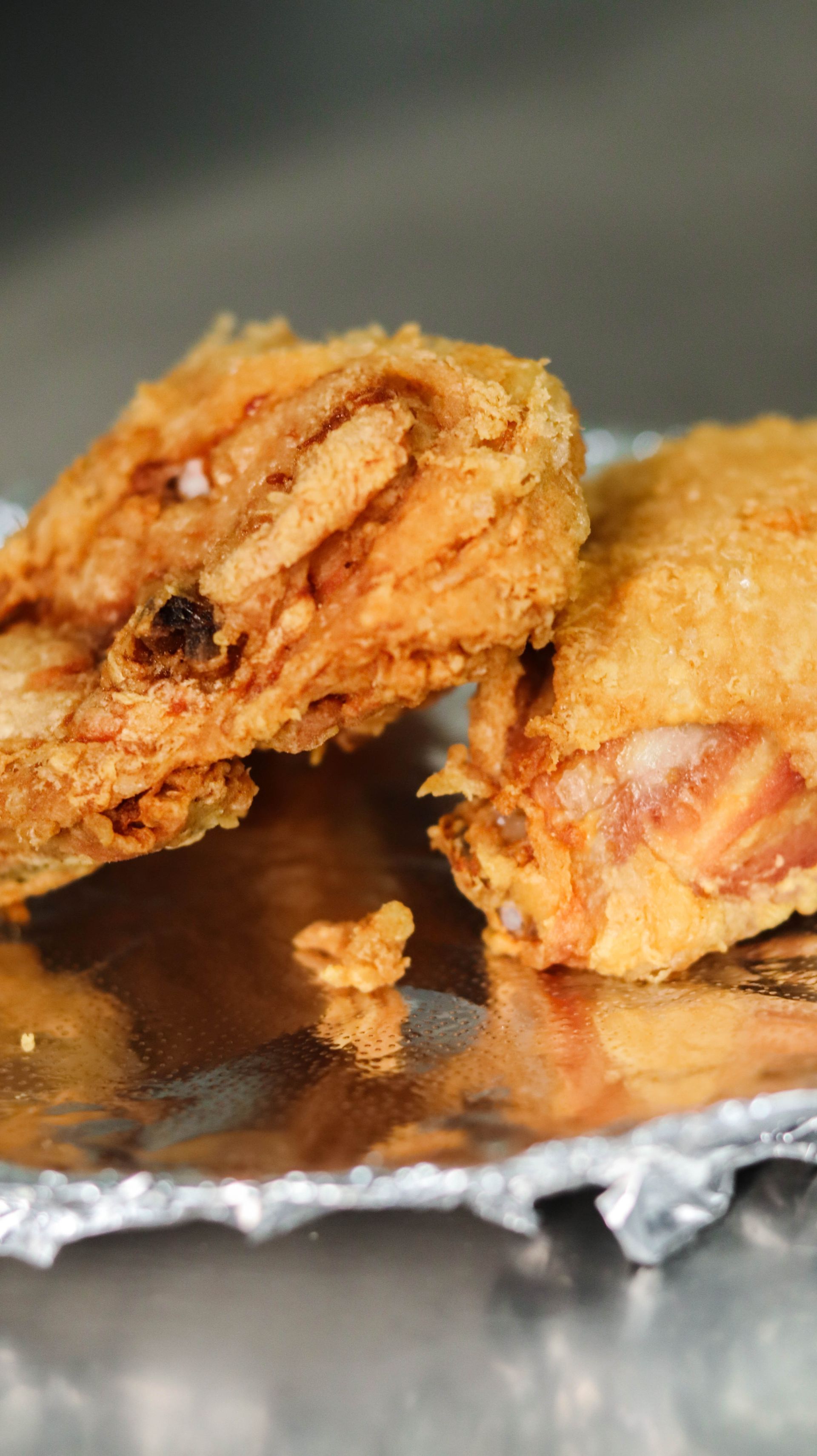 Two fried chicken wings are sitting on a piece of tin foil.