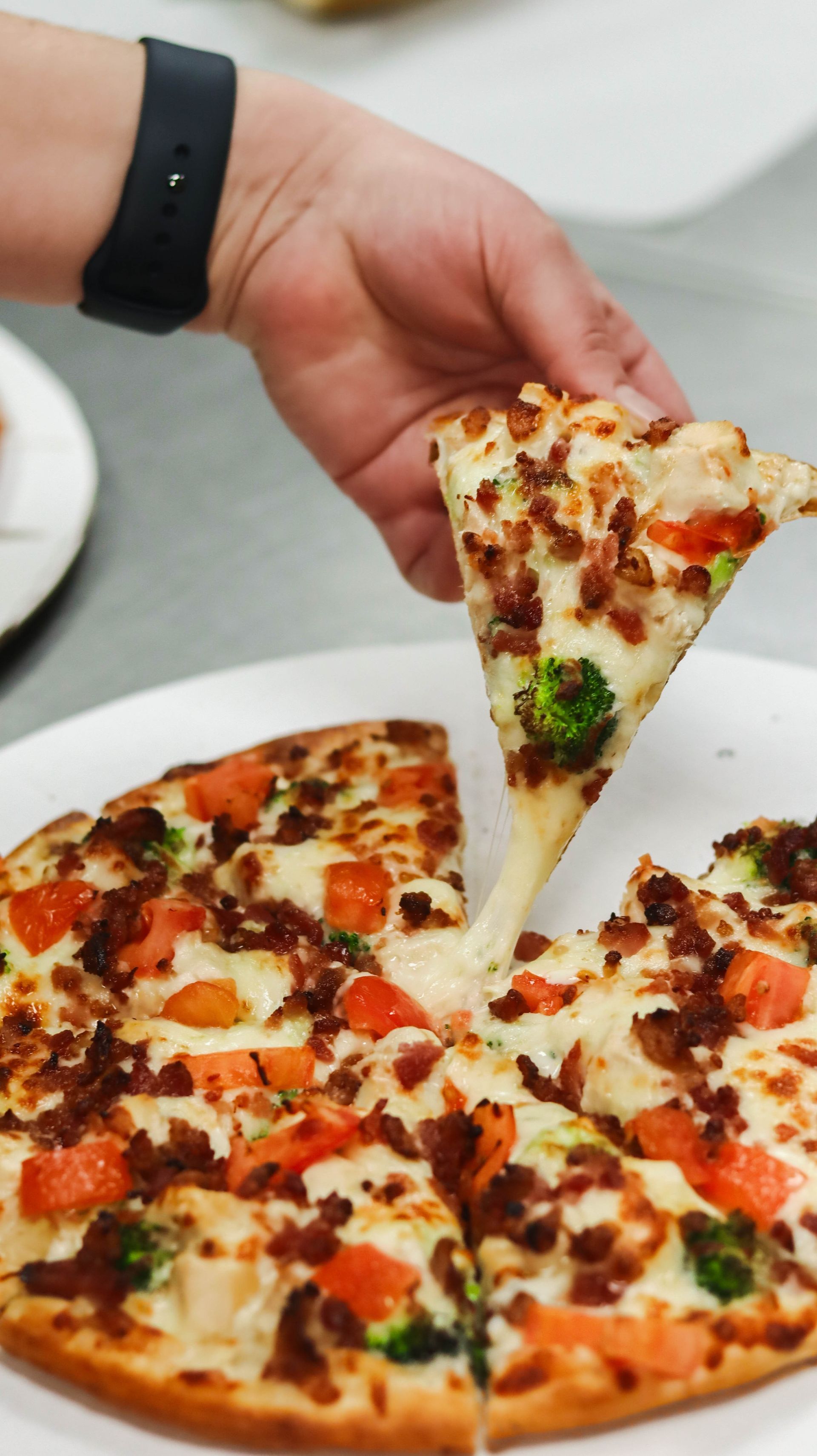 A person is taking a slice of pizza from a pizza on a plate.