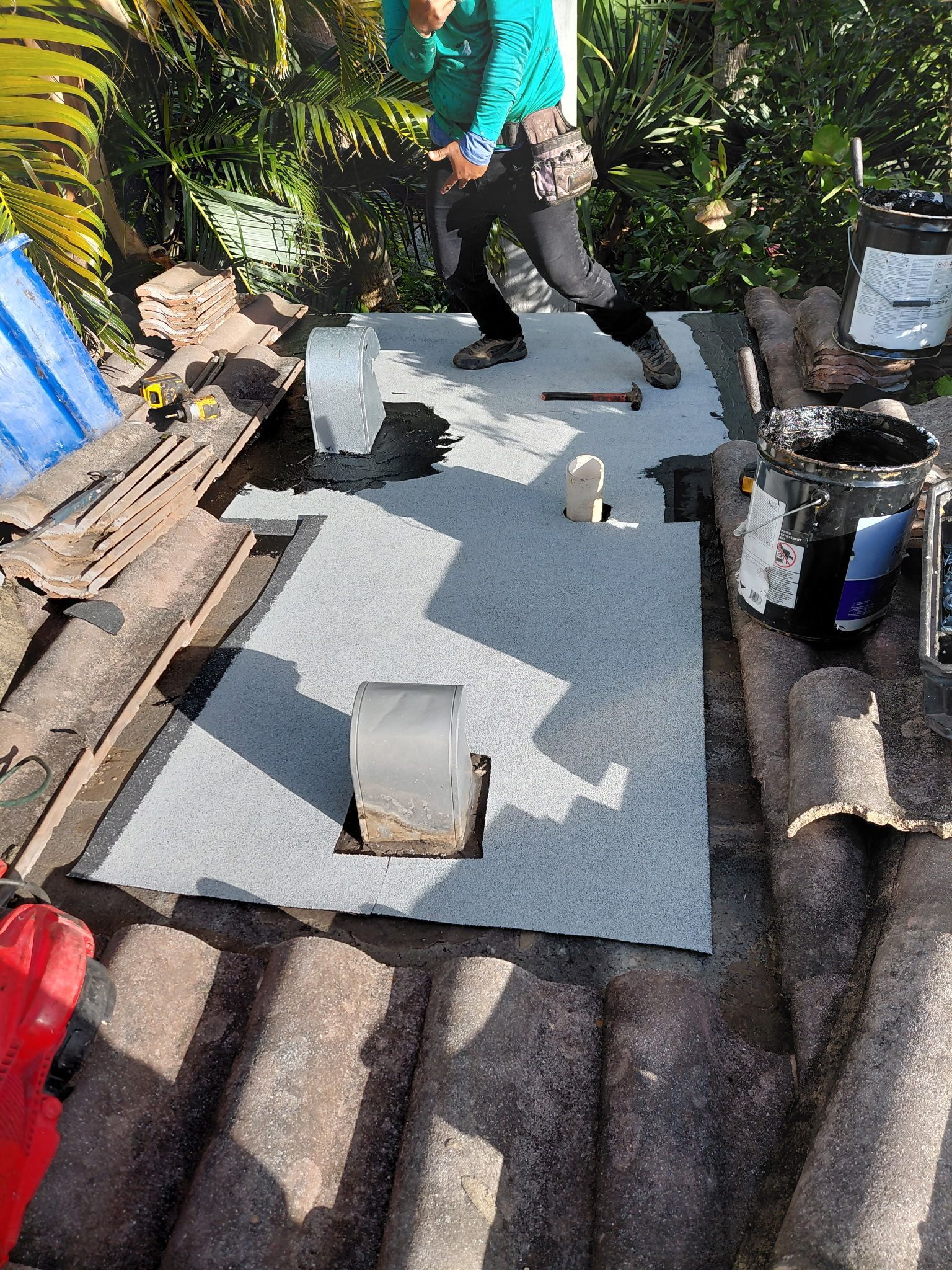 Person standing on a gray mat in a garden, with several small weights or blocks around it.