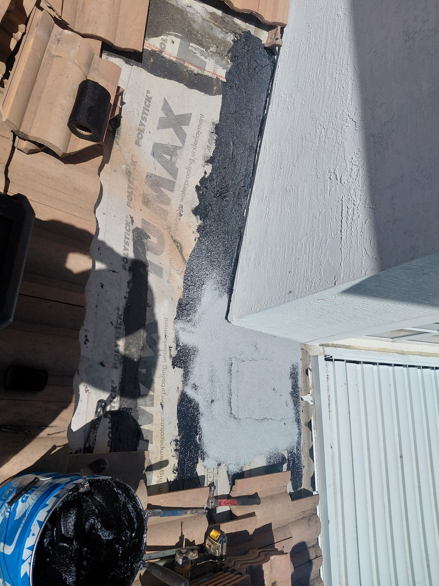 Rooftop with gravel and HVAC equipment beside a tan building and white siding