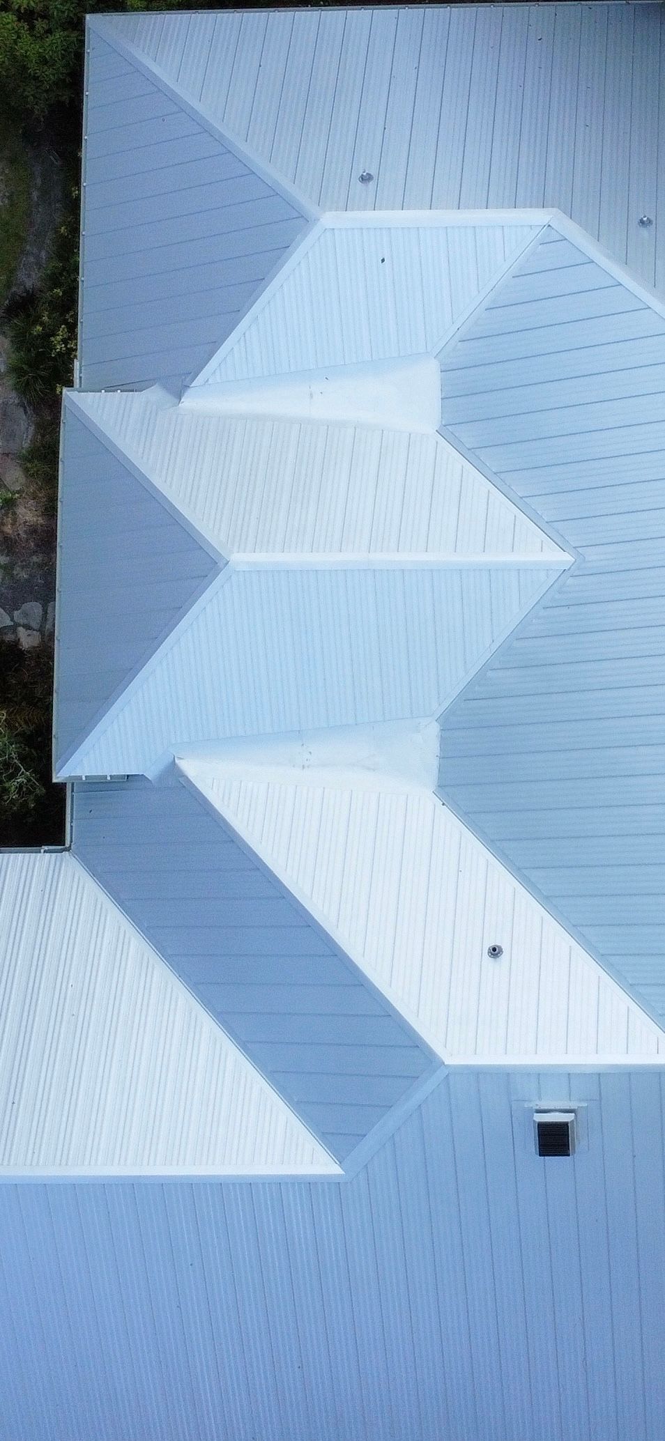 Abstract white geometric wall texture with layered angular panels and a small dark square near the bottom right