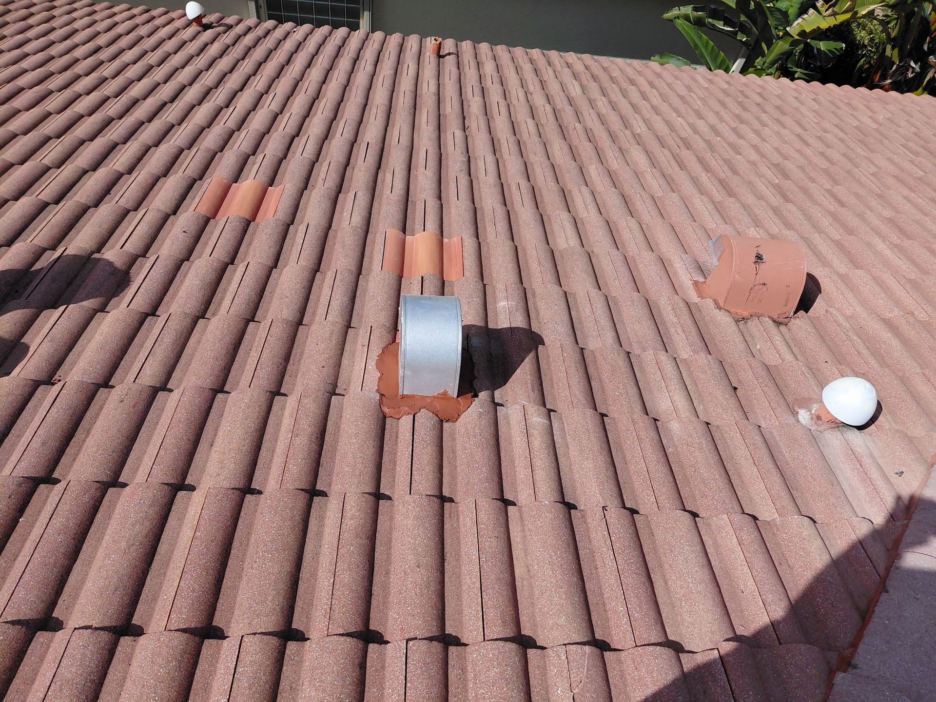 Rooftop with red tiles, several vents, and a small white ball near the lower right.