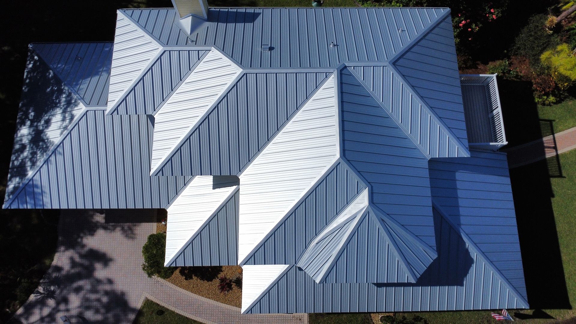 Aerial view of a blue metal roof with several white skylights and angled roof sections