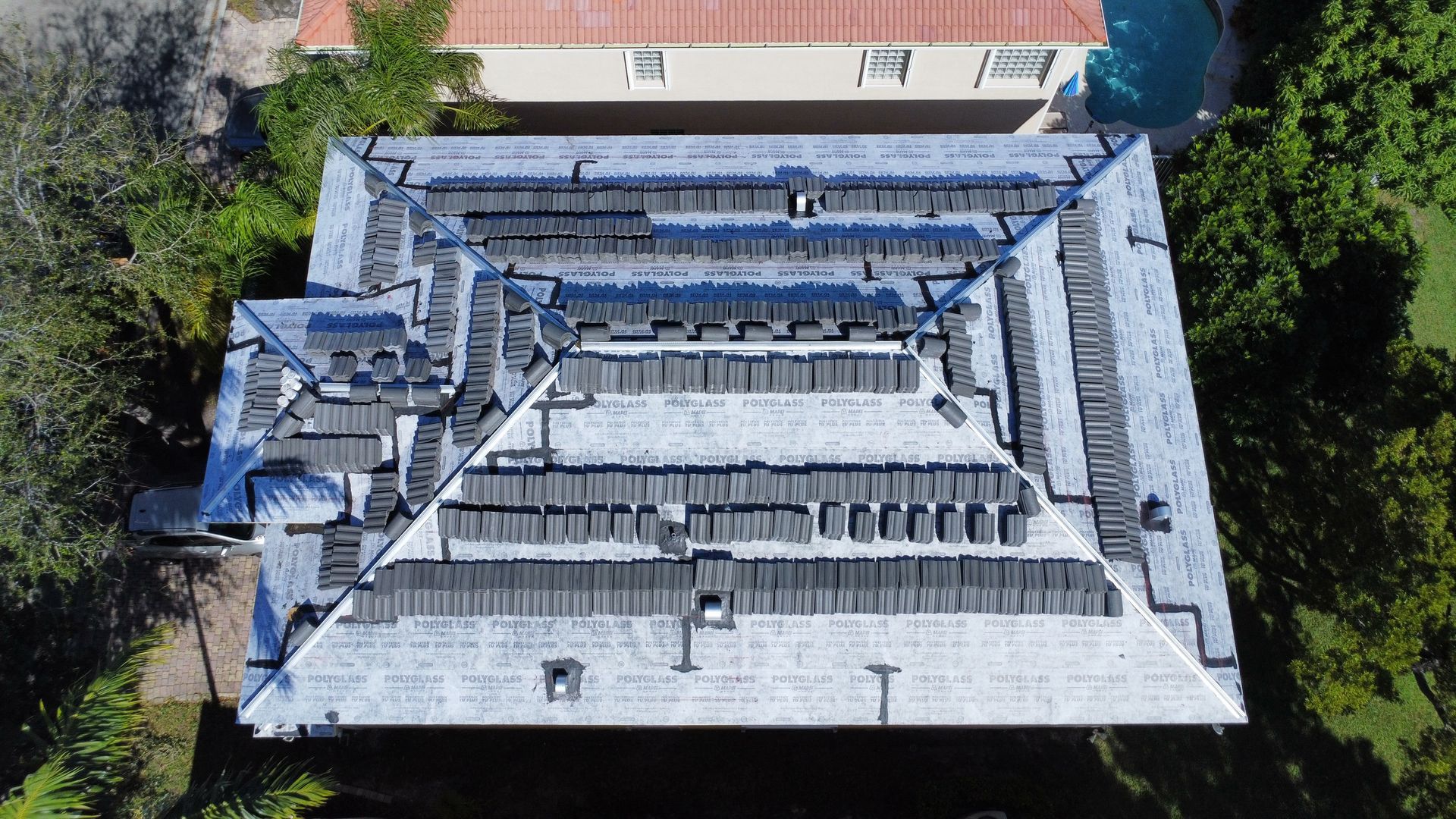 Aerial view of a gray-roofed building surrounded by trees and a courtyard